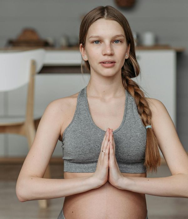 Pregnant woman in a peaceful yoga pose in a calm environment.